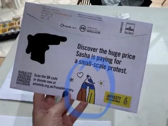 amnesty-international-vipustila-konvert-iz-zobrazhennyam-de-obiymayutsya-personazhi-u-kolorakh-praporiv-ukrayini-ta-rosiyi