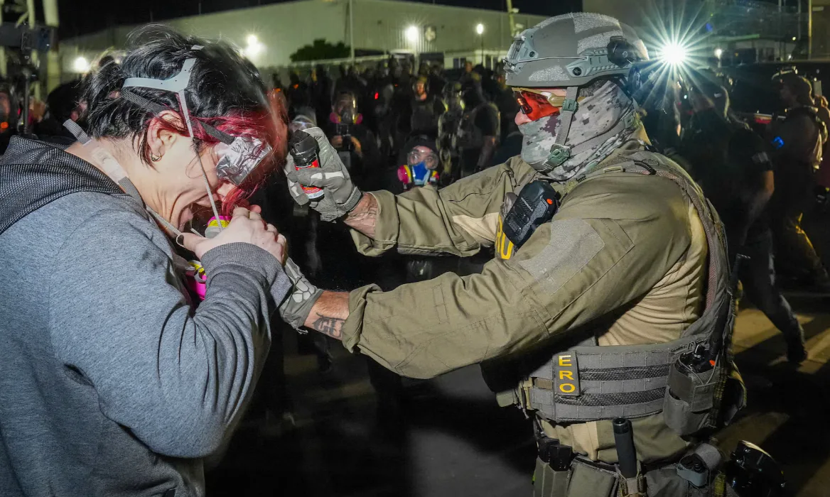 An ERO agent sprays pepper spray into a protester's gas mask outside Delaney Hall in Newark, New Jersey. Photo: Reuters